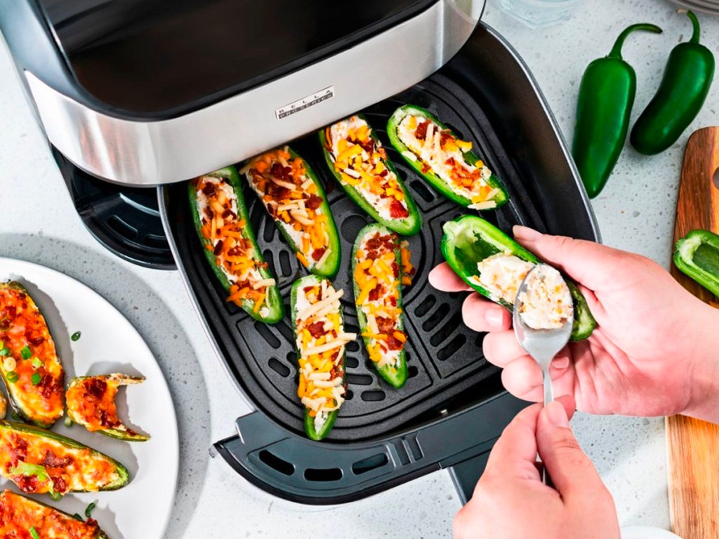someone putting jalapeno poppers into air fryer basket