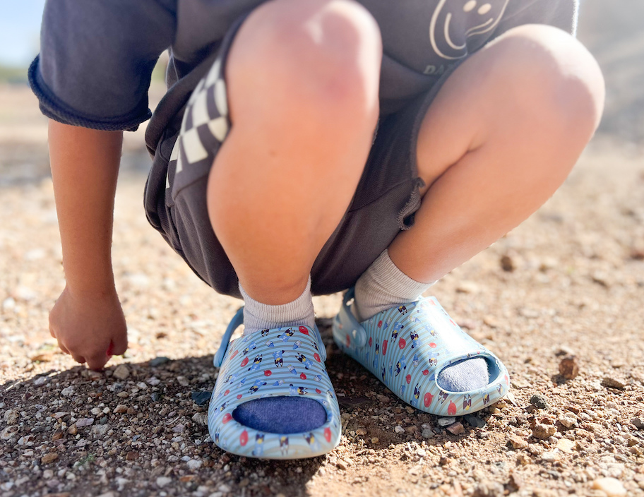 close up of child wearing bluey crocs in dirt