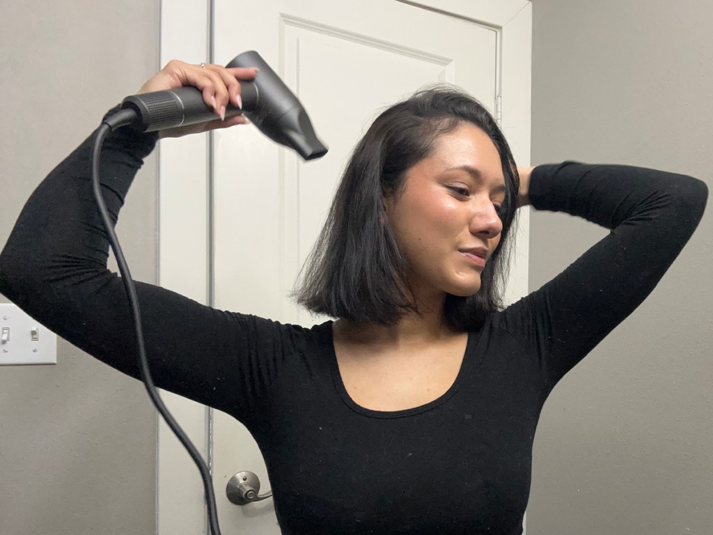 woman in black shirt holding gray hair dryer
