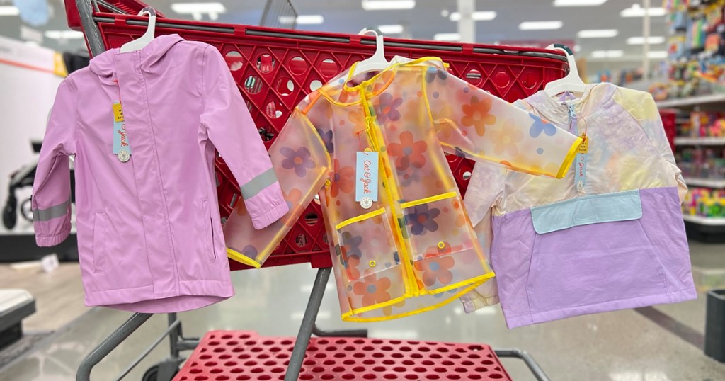three kids raincoats hanging on target shopping cart