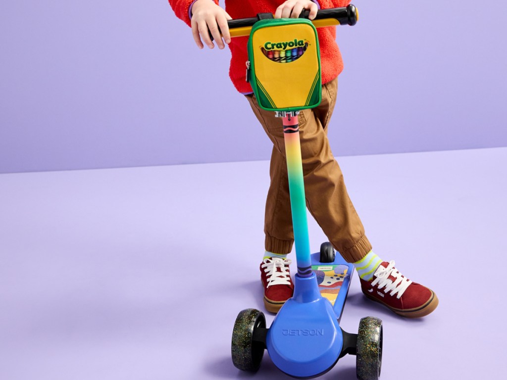 child using crayola scooter in a. purple background