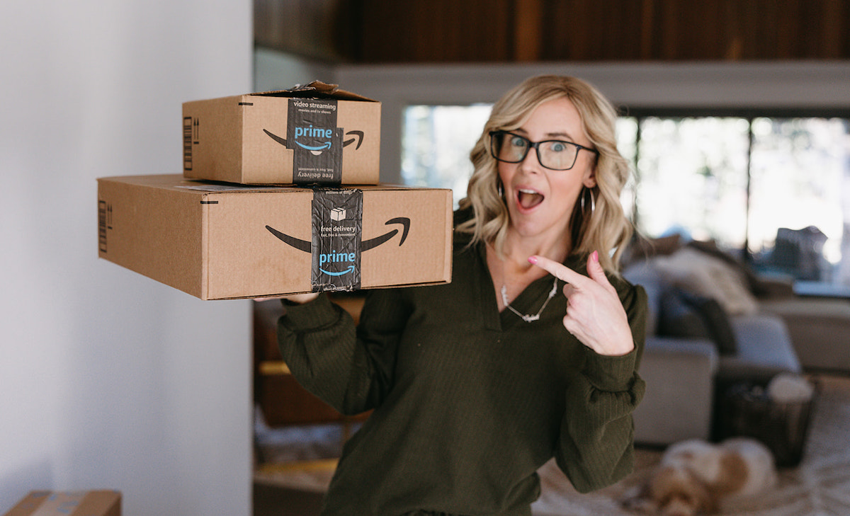 woman standing in hallway holding amazon boxes 