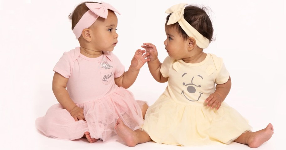 two baby girls wearing disney dresses and headbands