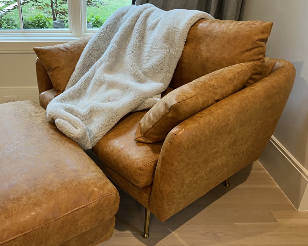 tan leather accent chair with white throw blanket 