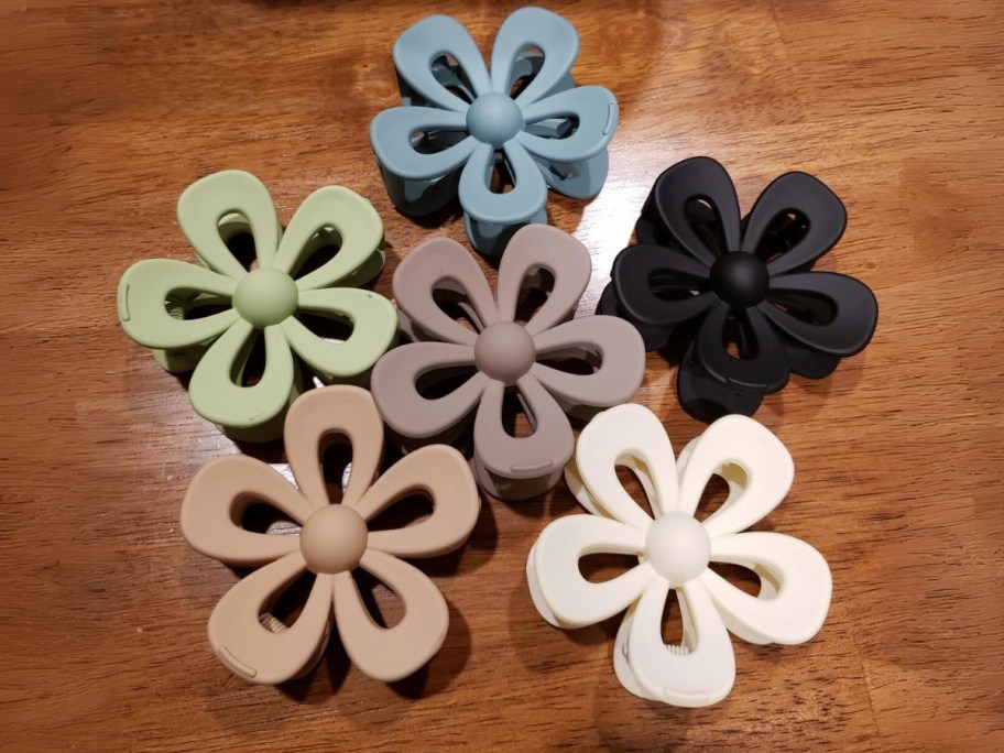 6 different color daisy style flower claw hair clips laying on a table 