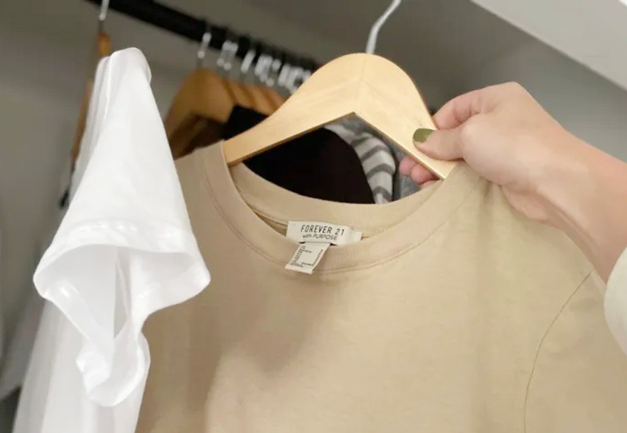 hand pulling tan shirt out of closet on hanger