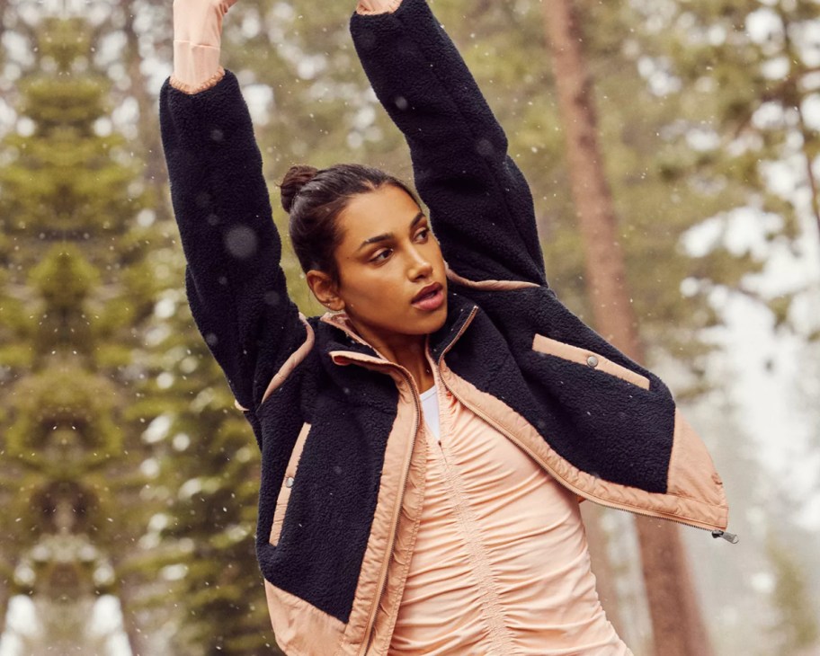 women with hands in air wearing black jacket