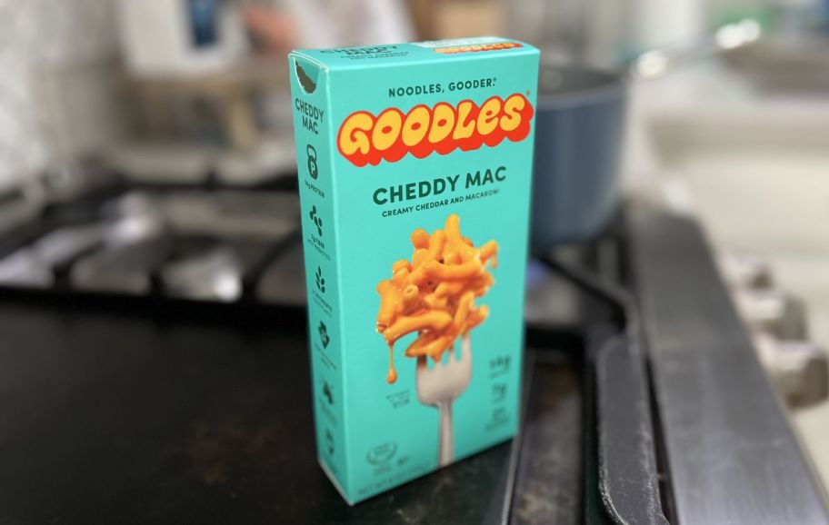 a box of goodles cheddy mac sitting on top of a gas stove