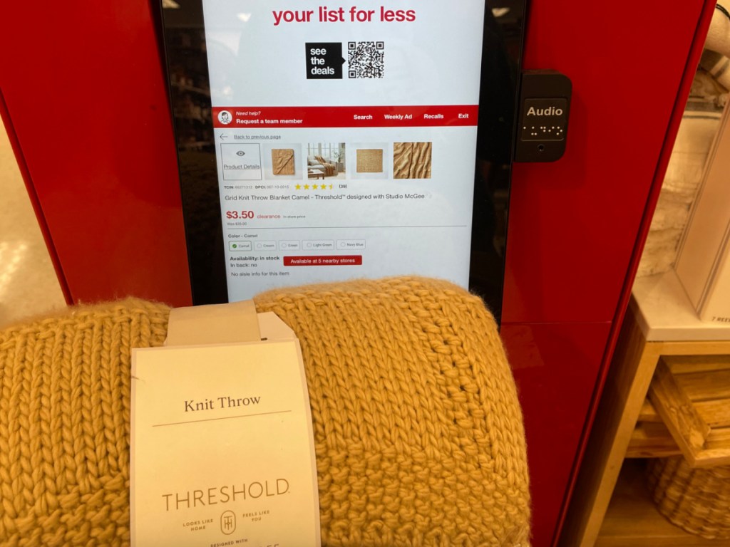 hand holding Threshold designed with Studio McGee Grid Knit Throw Blanket in front of target price checker