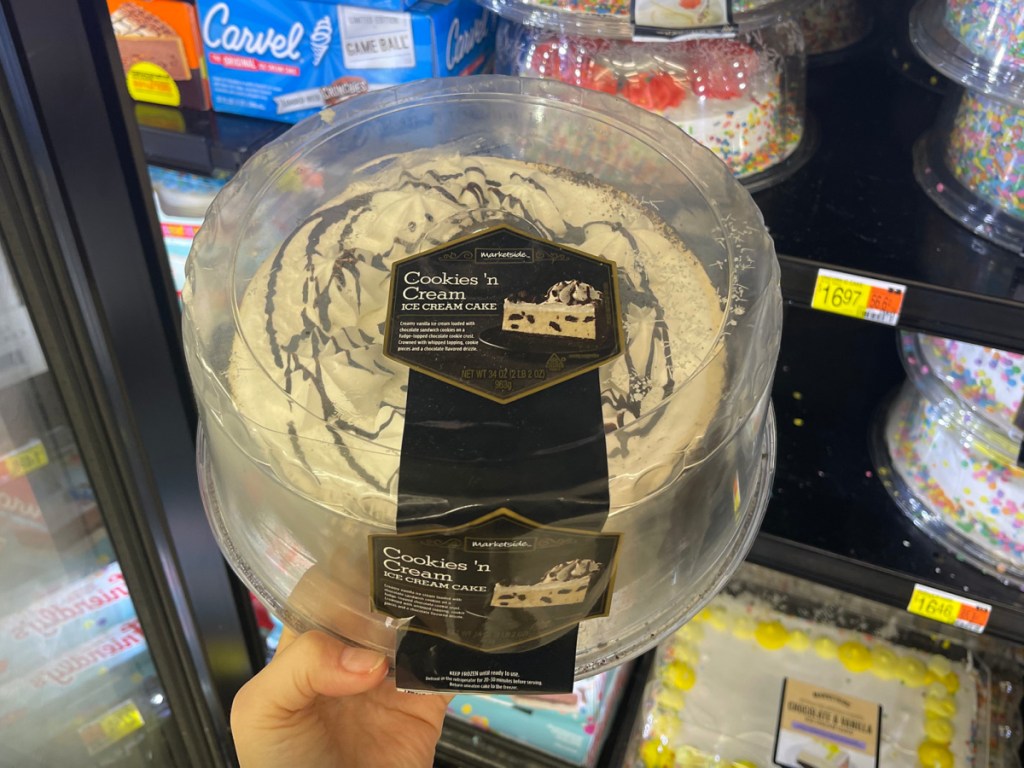 hand holding a market side cookies and cream ice cream cake inside of a Walmart freezer