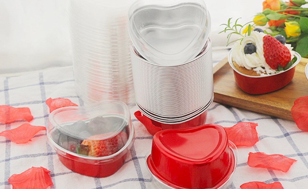 heart shaped red tins with lids, and rose petals on table