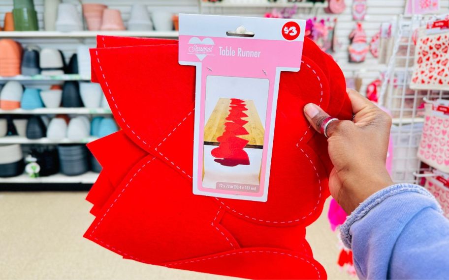 a womans hand holding a red felt heart table runner