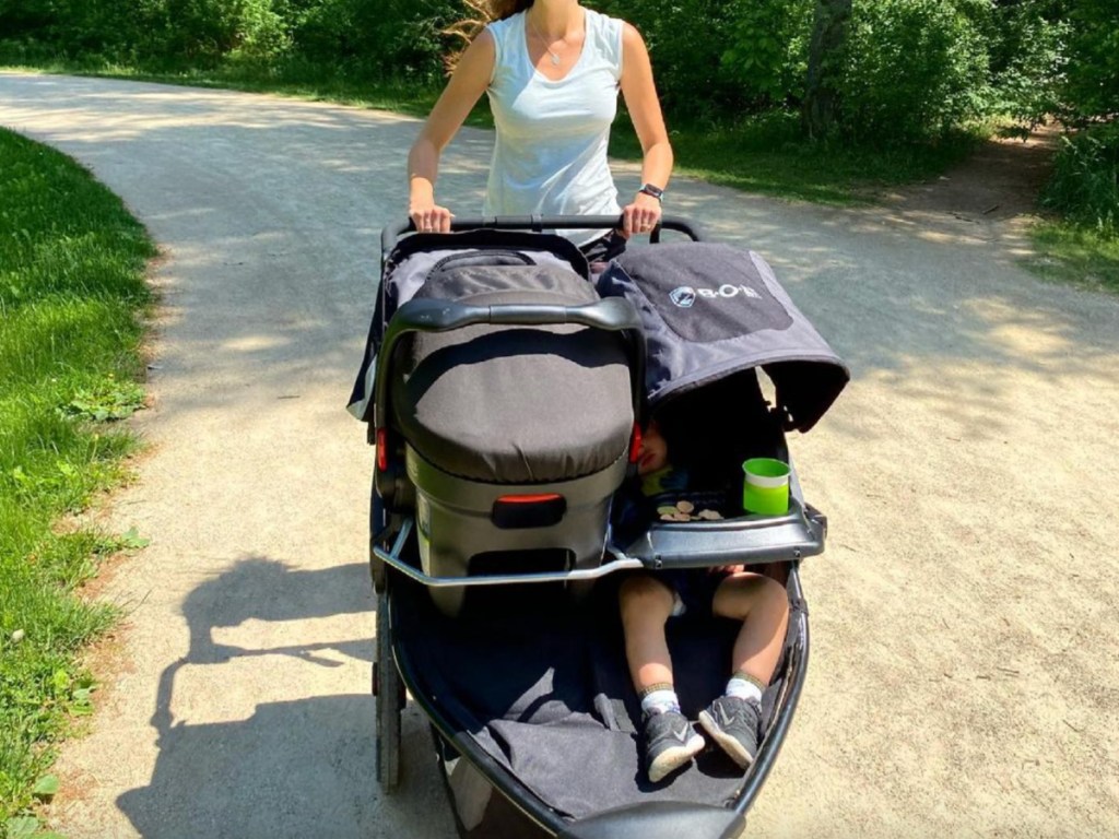 woman pushing bob double jogging stroller with toddler on one side