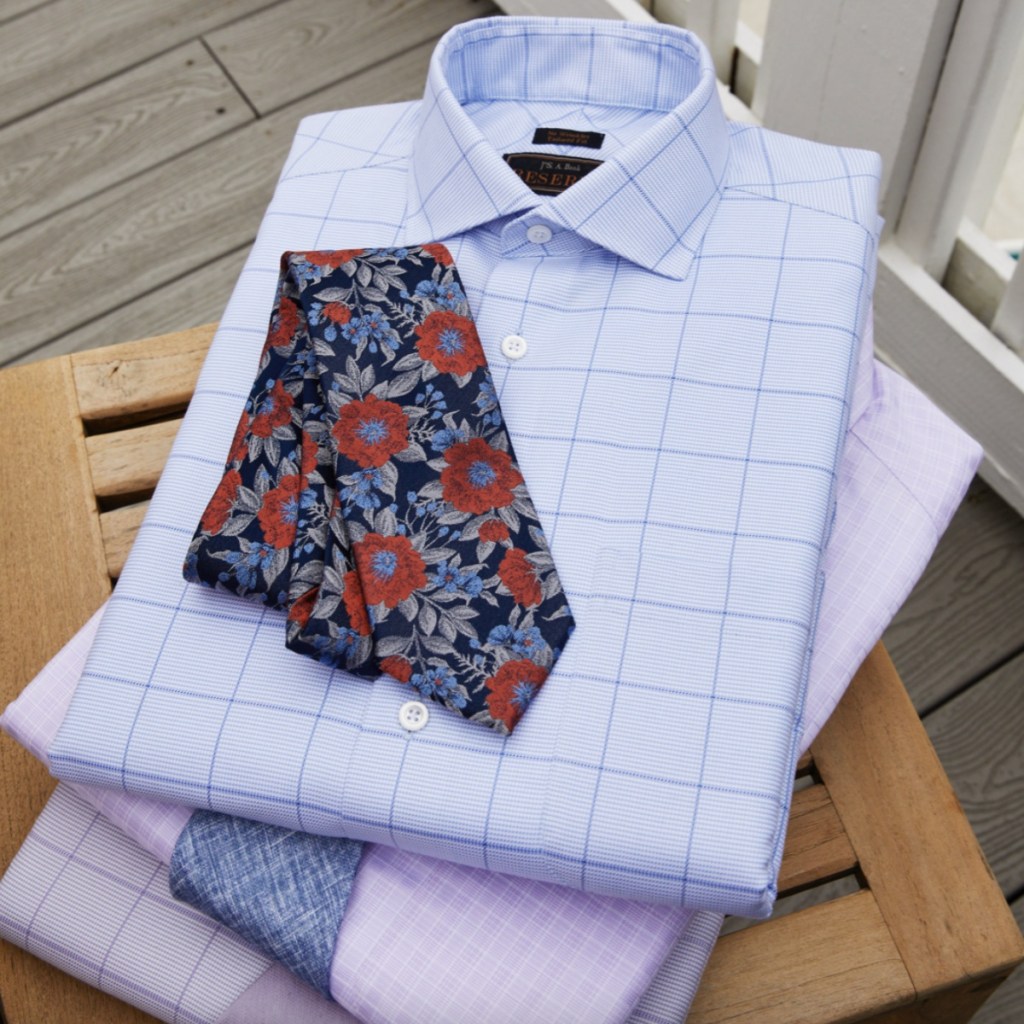 pile of folded dress shirts with tie on top 