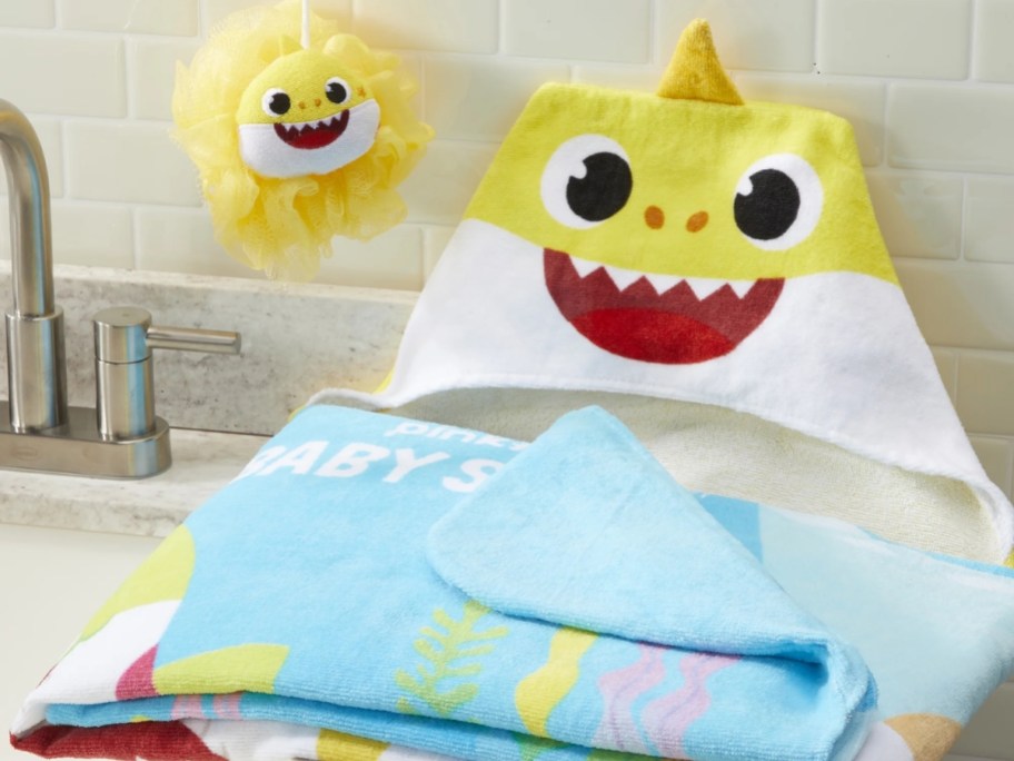 baby shark hooded towel and loofah on a sink