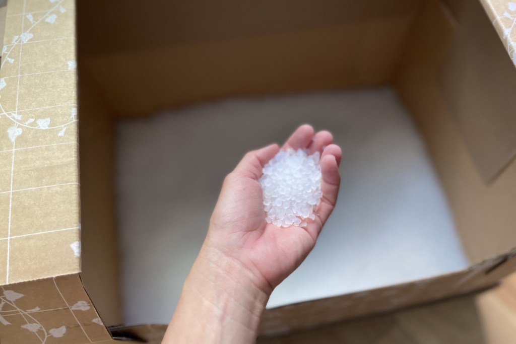 hand holding silica cat litter over box