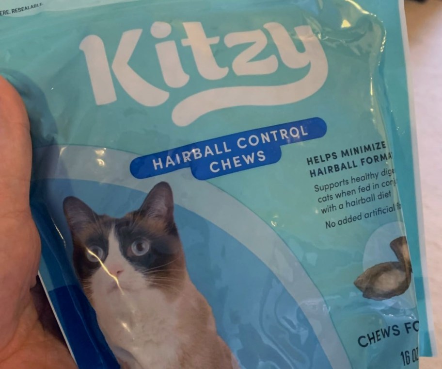 holding a bag of hairball control cat treats