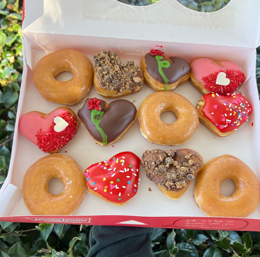 hand holding box of valentines doughnuts