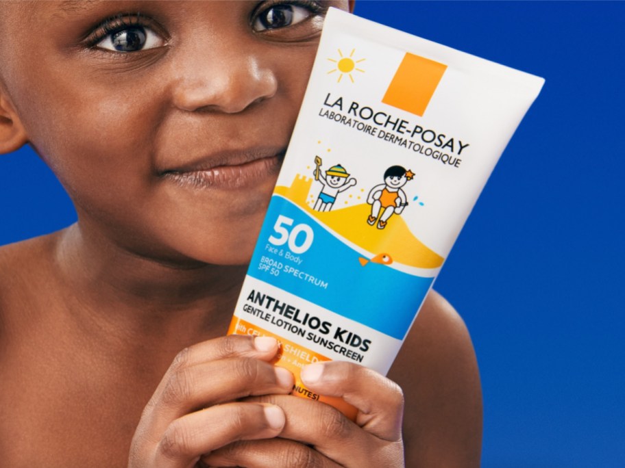 kid holding bottle of sunscreen