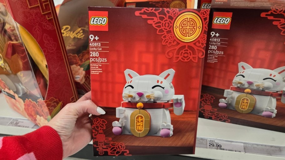 womans hand holding a lego lucky cat building set