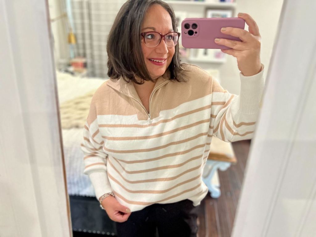 woman taking mirror selfie with beige and white sweater 