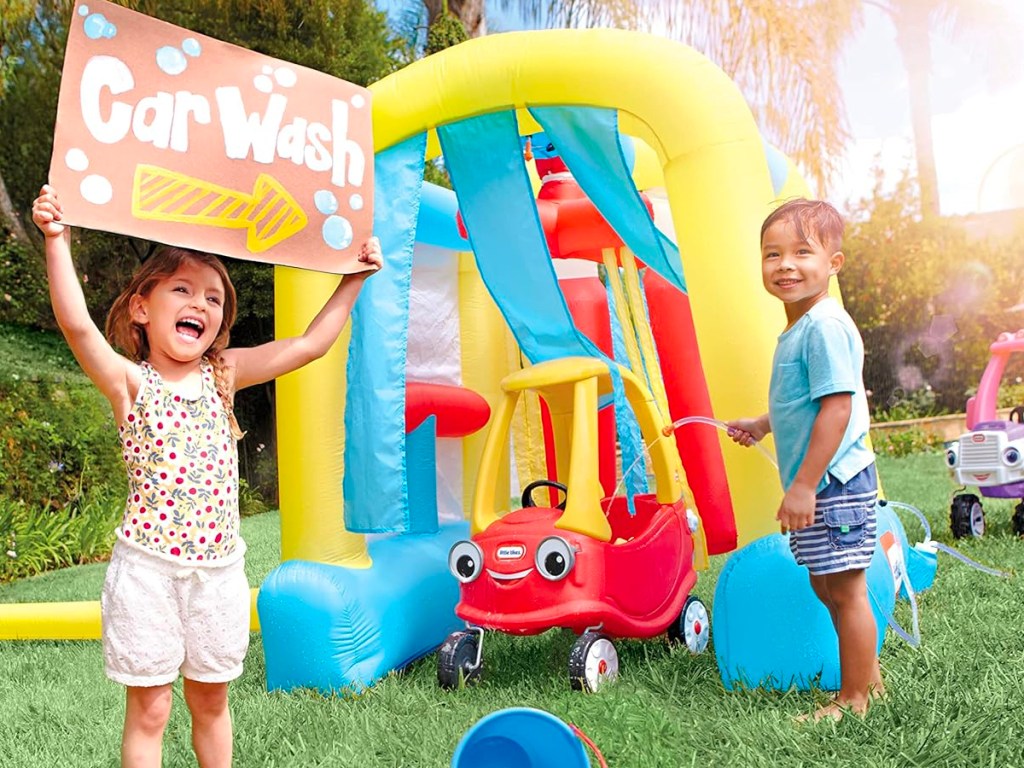 kids playing next to little tikes blowup car wash 