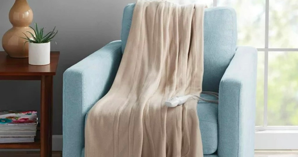 beige blanket sitting on blue chair next to window