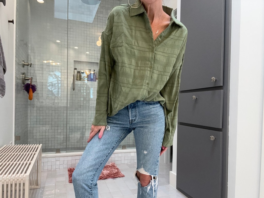 woman wearing green top with jeans in bathroom