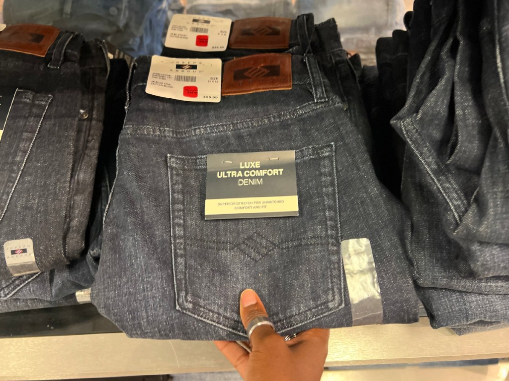 hand pulling mens jeans off of shelf