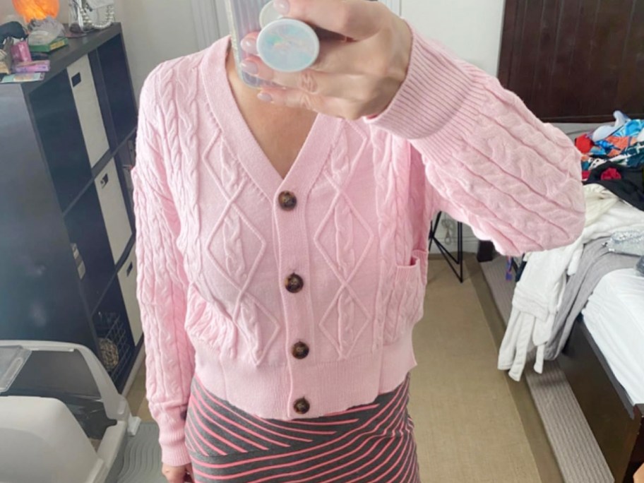 woman taking photo of herself in pink cardigan