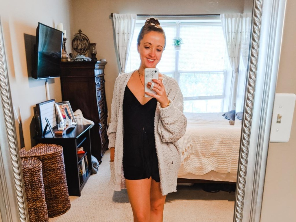 woman wearing sweater taking selfie in bedroom