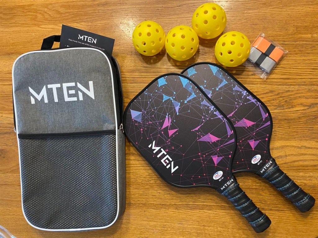 two pickleball paddles laying on table with yellow balls, grip tape and bag