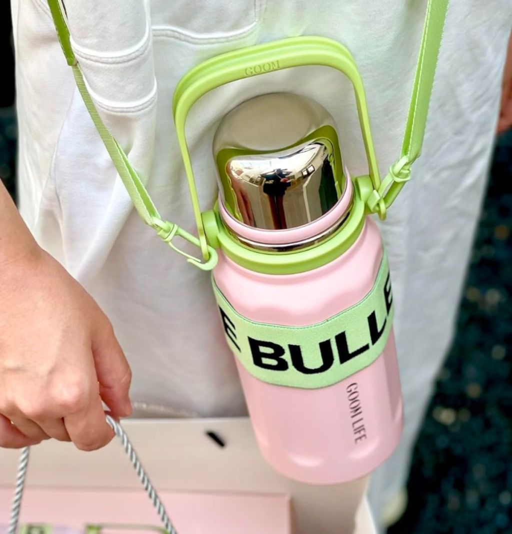 a woman wearing the Insulated Beverage Thermos with Lid, Flexible Strap Wide Mouth pink with crossbody strap