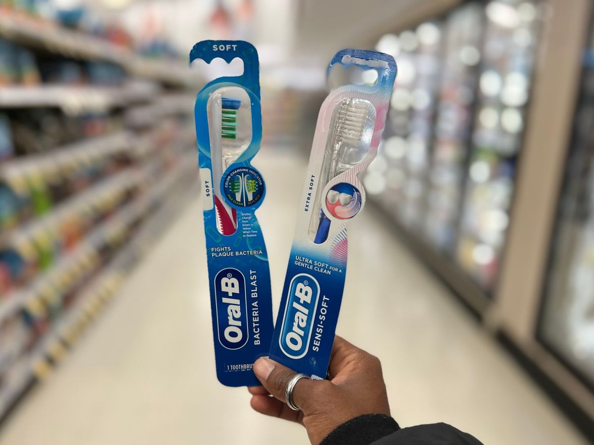 two toothbrushes being held up in store aisle