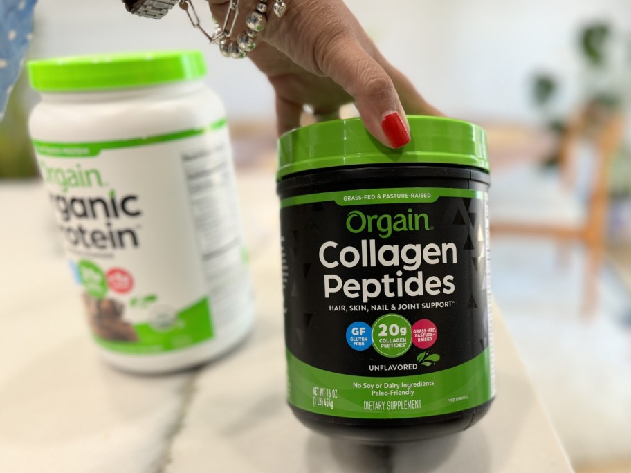 hand touching a black and green jar of orgain collagen powder