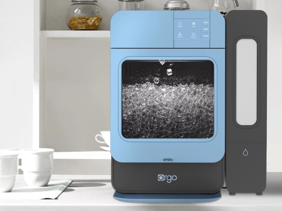 blue countertop ice maker with ice inside sitting on the counter