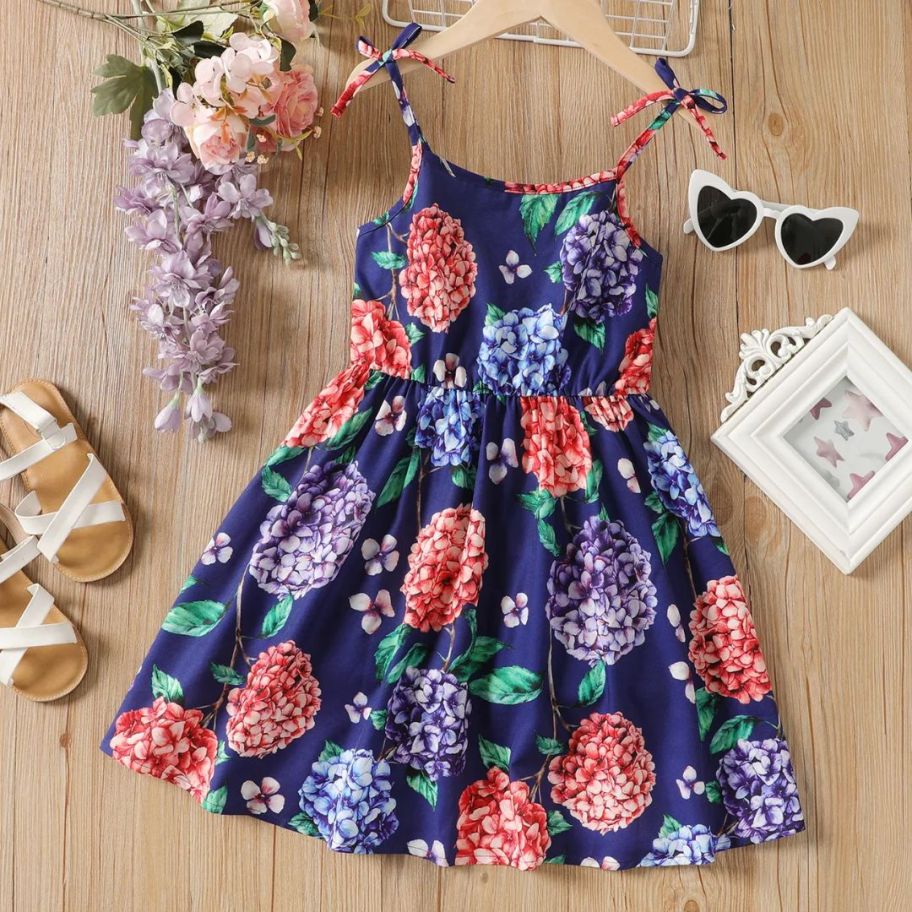 little girl's navy floral dress laid out on floor with flowers and accessories