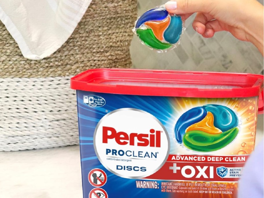 persil plus oxi detergent pacs 38 count shown with womsns hand holding the pod