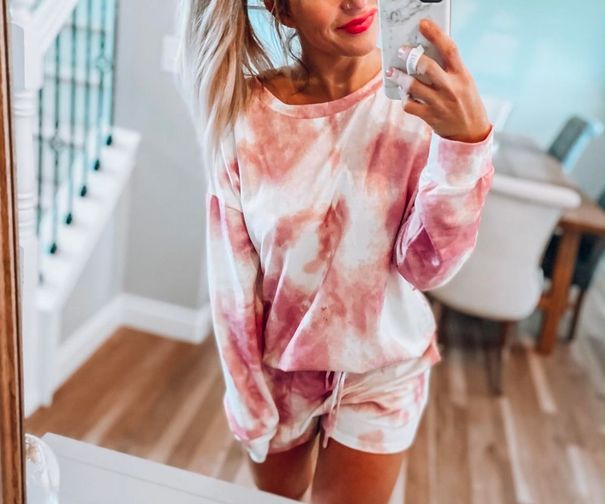  a woman wearing a dark red tie dye shirt and shorts taking a selfie