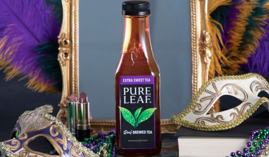 a bottle of pure leaf extra sweet tea in front of a mirror with two mardi gras masks