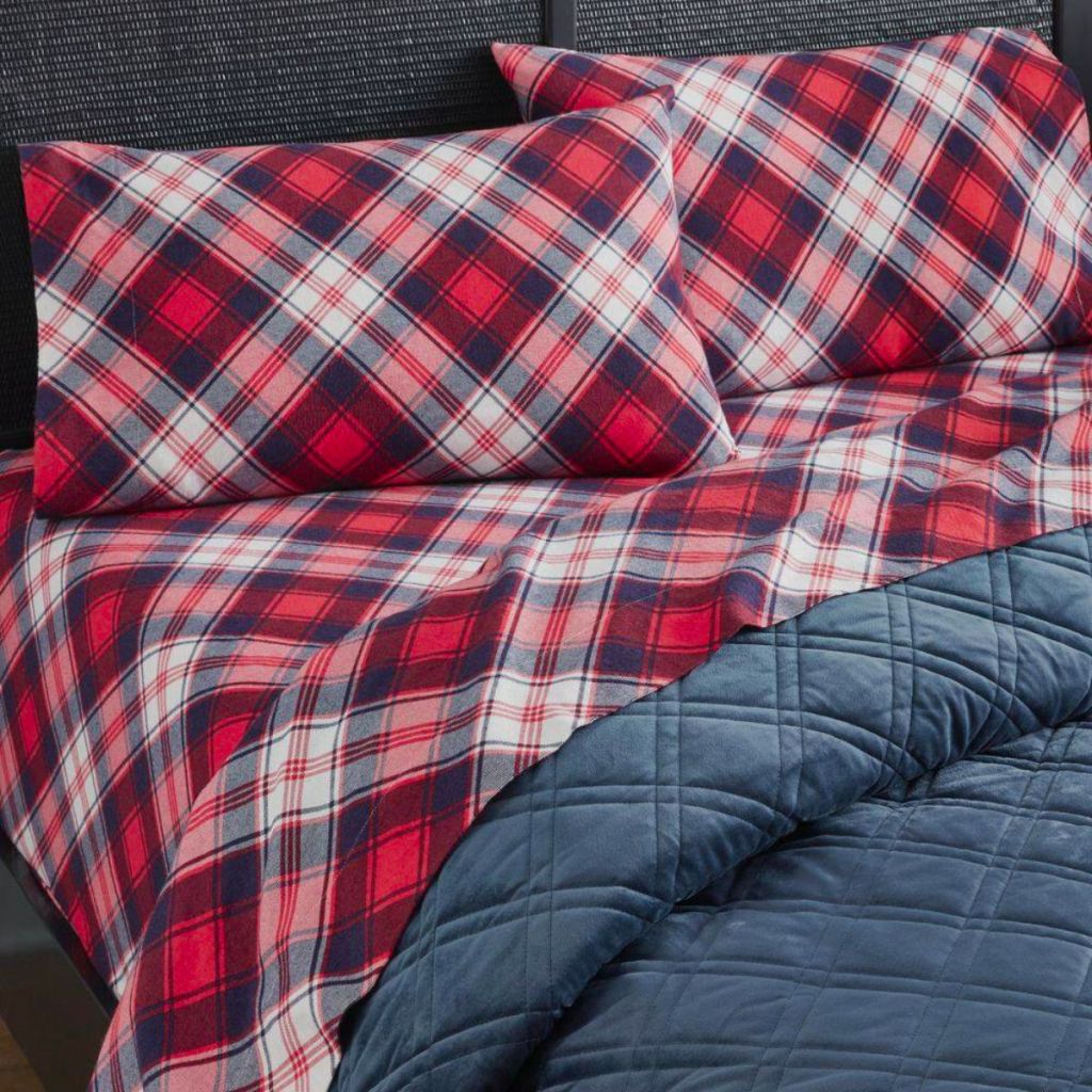 red plaid flannel sheet set on a bed with a blue bedspread