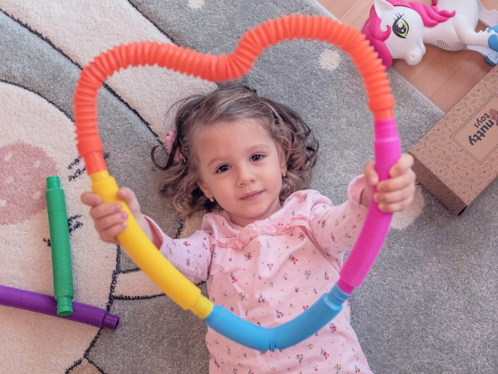 toddler holding up sensory Pop Tubes in the shape of a heart