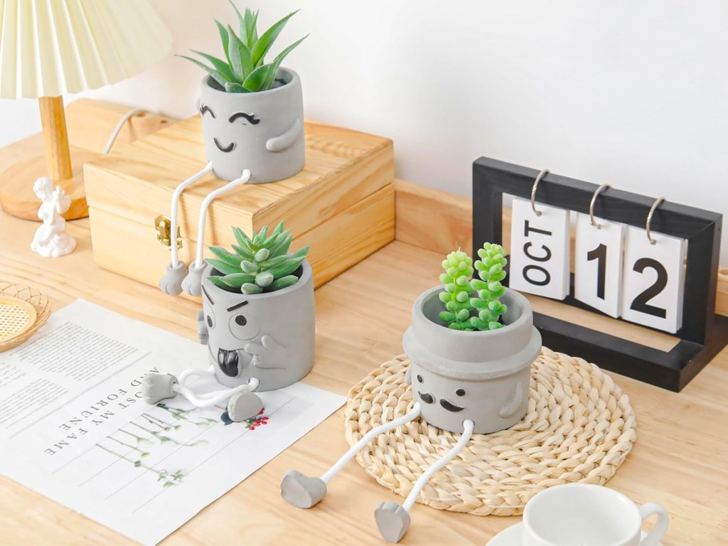 3 gray artificial succulent pots sitting on table