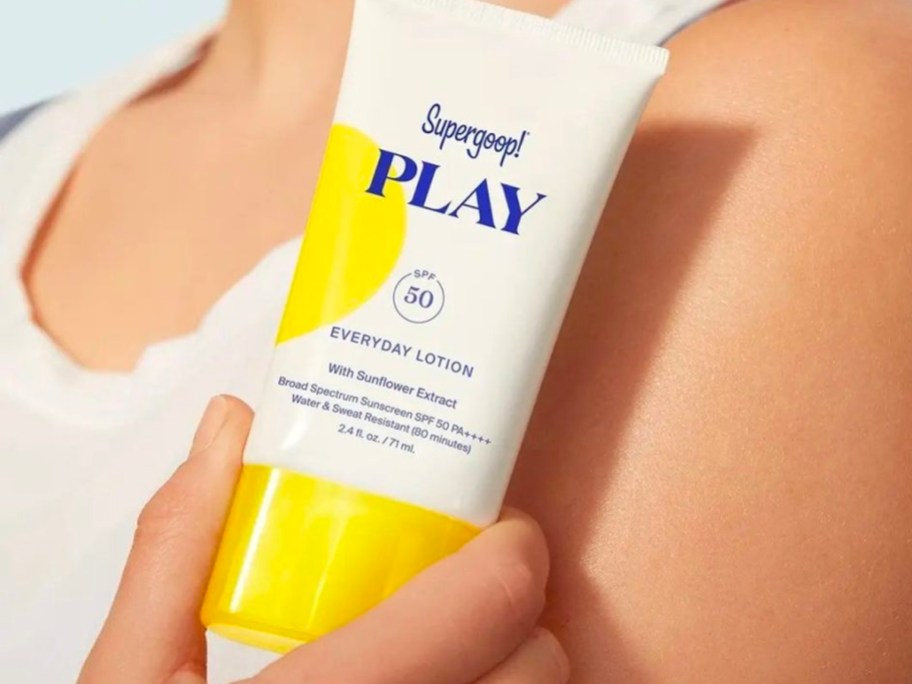 woman holding supergoop play spf 50 sunscreen lotion bottle