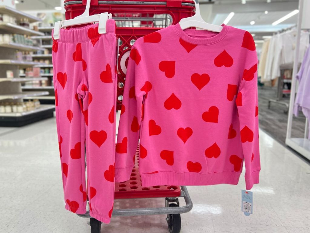pink sweatshirt and pink pants with red hearts hanging on cart at Target
