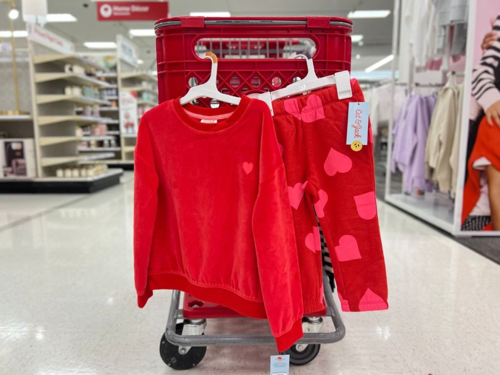 red velour girl's top with a pink heart and matching red pants with pink hearts hanging on Target cart