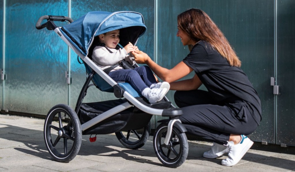 woman bending down looking at toddler in stroller