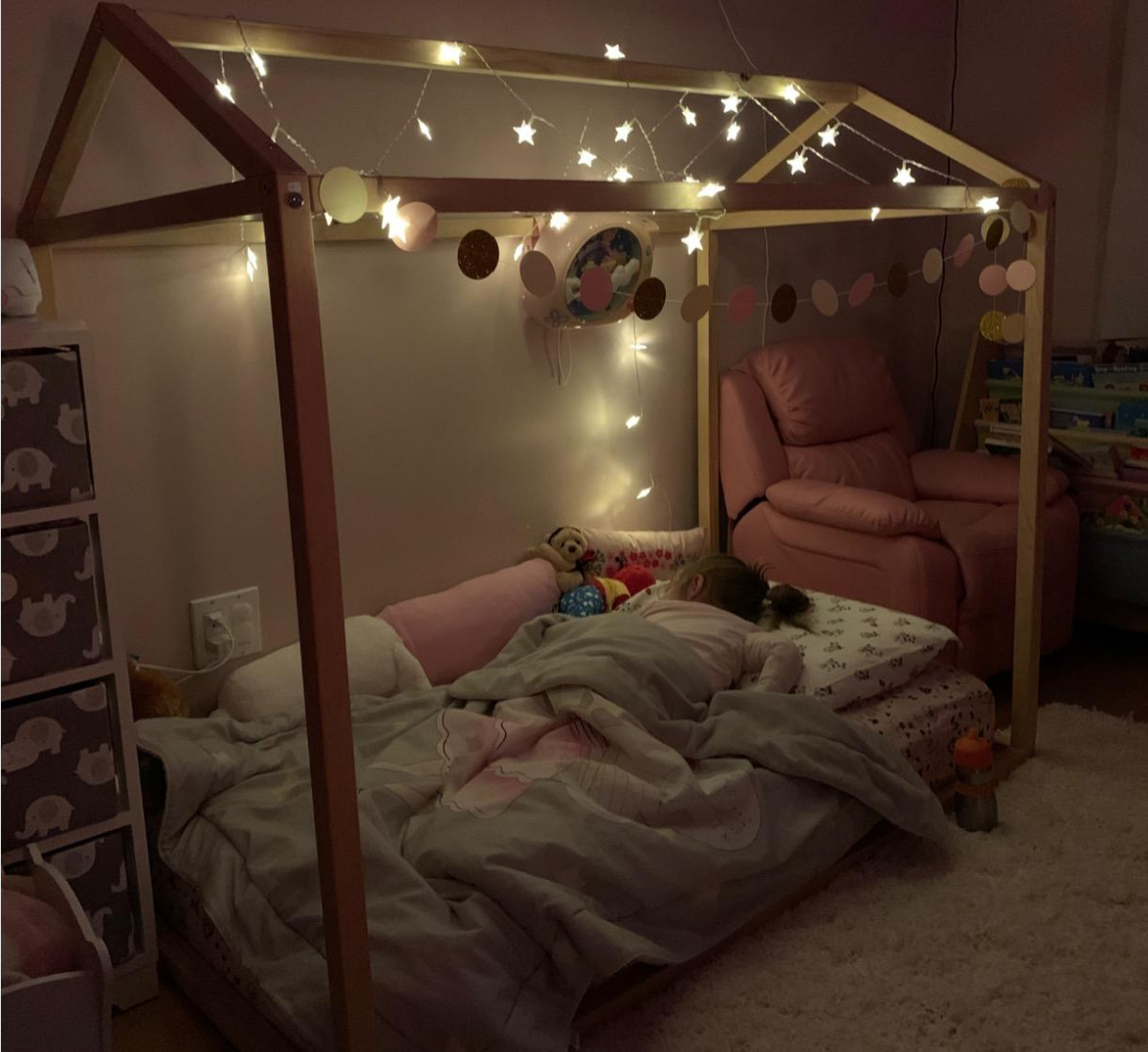 wooden kids bed with string lights above it