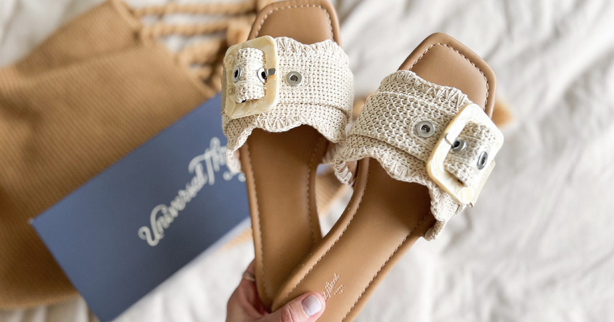 hand holding pair of beige sandals 