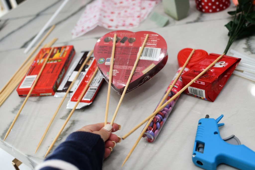 using hot glue to secure wood skewers to candy